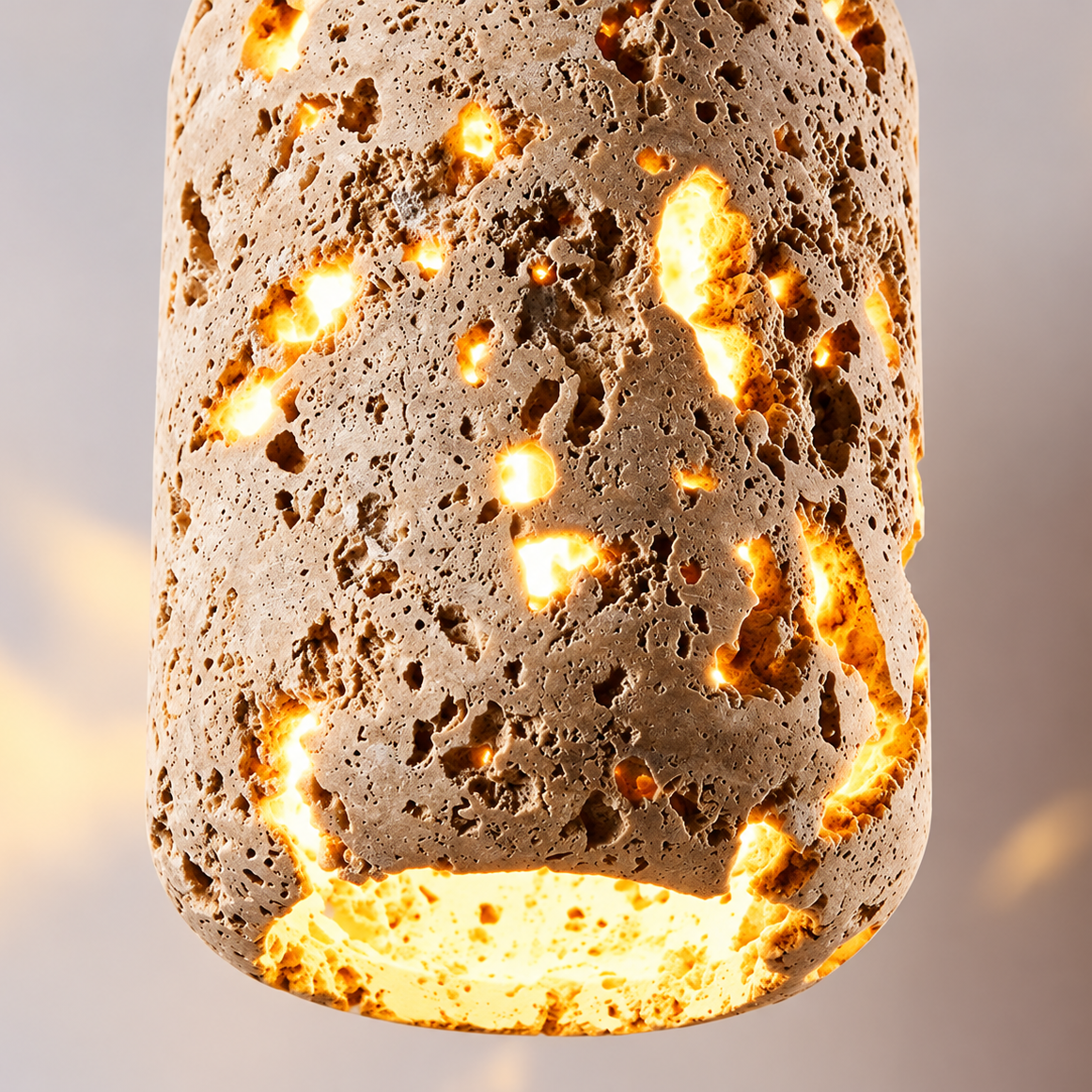 Gros plan sur les cavités du travertin de l'applique CAVA traversées par la lumière – Ambiance Éclat
