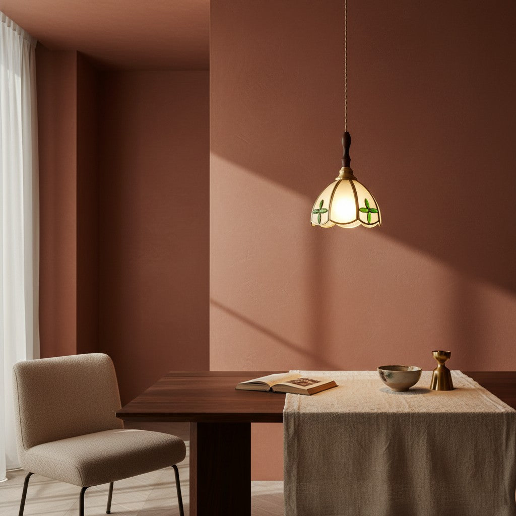Suspension TROPEA en verre crème à motif de feuilles, allumée au-dessus d'une table devant un mur terracotta – Ambiance Éclat